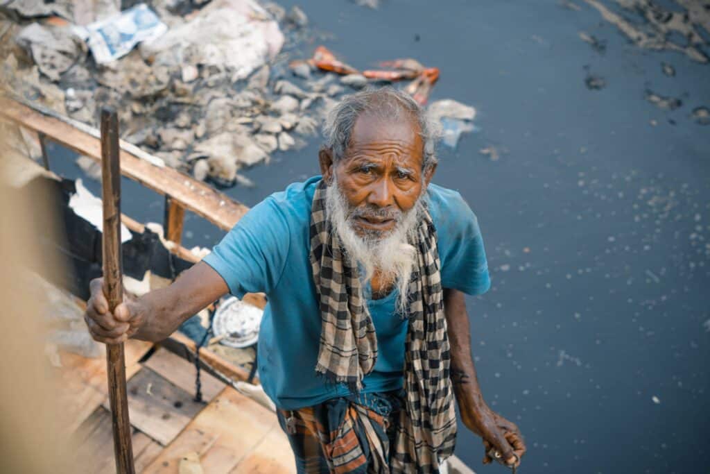 Vieillard sur un bateau entouré de pollution