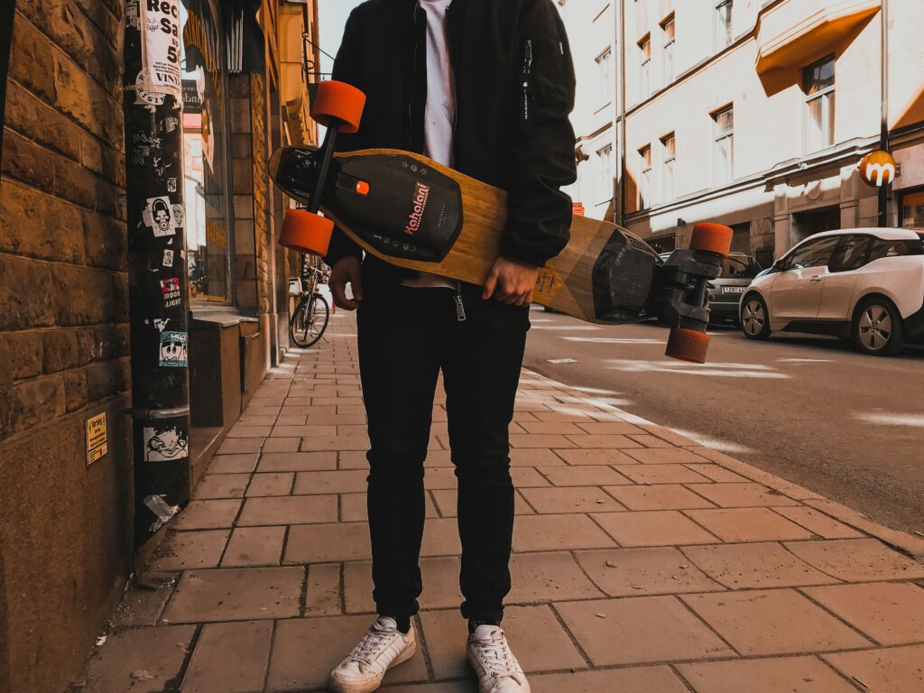 Homme qui tient un longboard éléctrique dans sa main